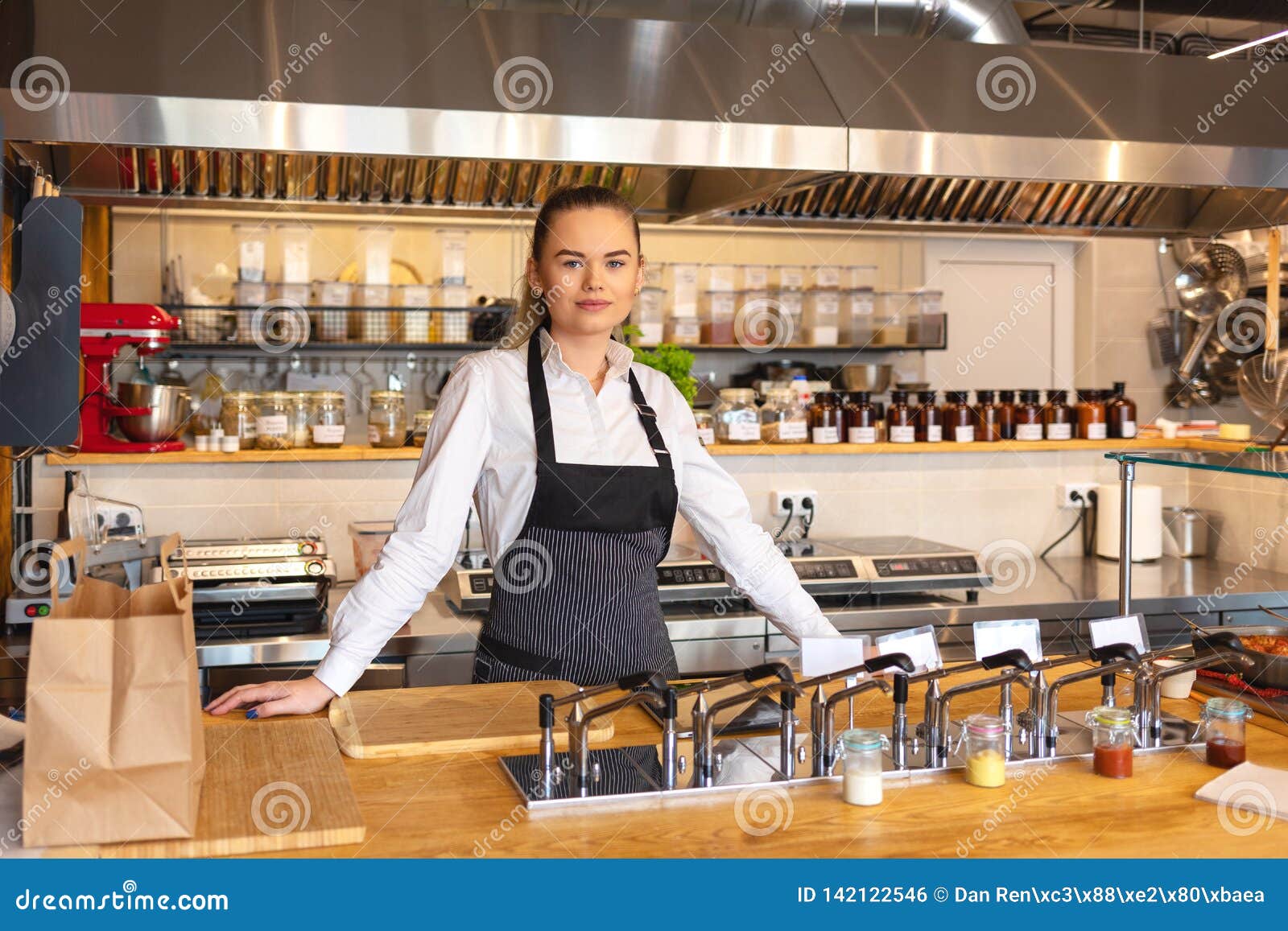 portrait of young woman standing behind kitchen counter in small eatery